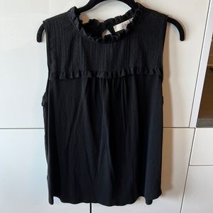 Black sleeveless top with ruffle details around neck
